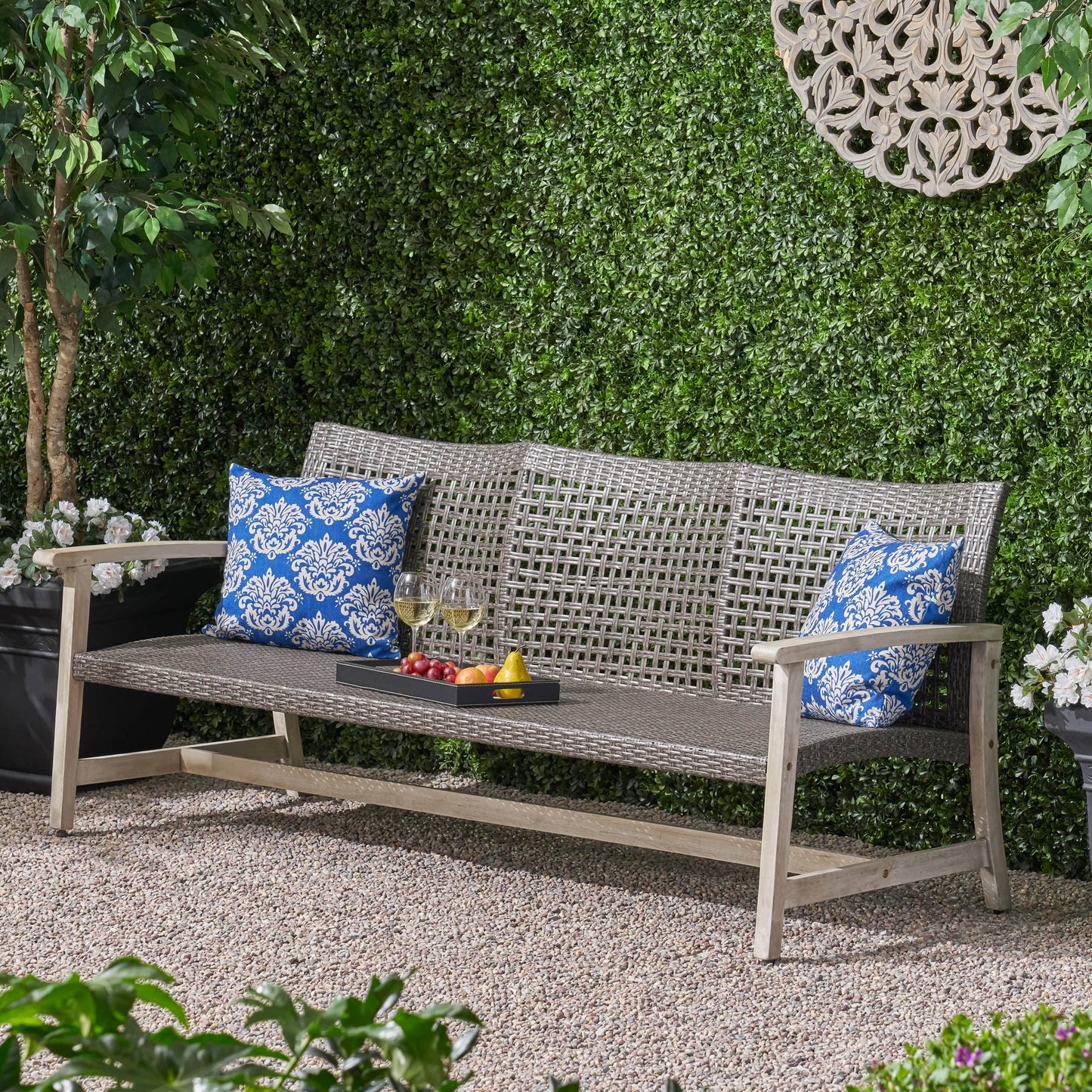 Outdoor Acacia Wood Wicker 3 Seater Sofa with blue patterned cushions in a lush garden setting on Tampa Home & Garden Store