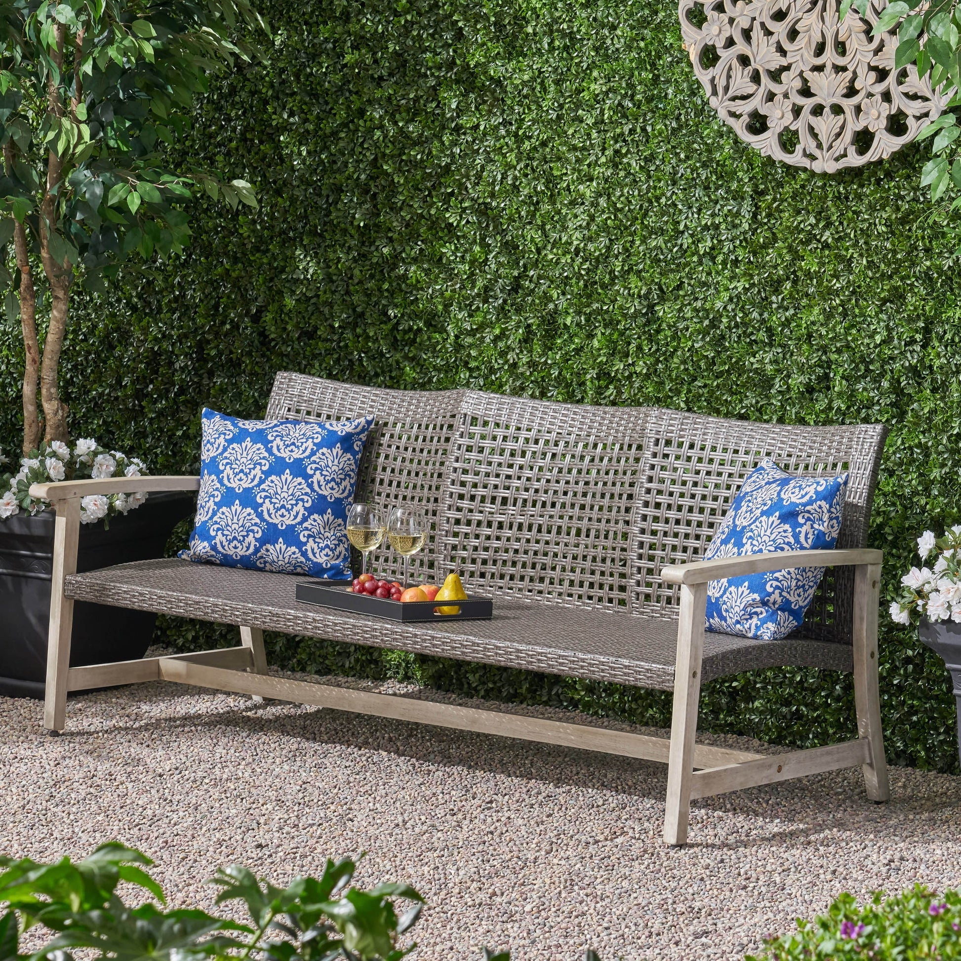 Outdoor Acacia Wood Wicker 3 Seater Sofa with blue patterned cushions in a lush garden setting on Tampa Home & Garden Store