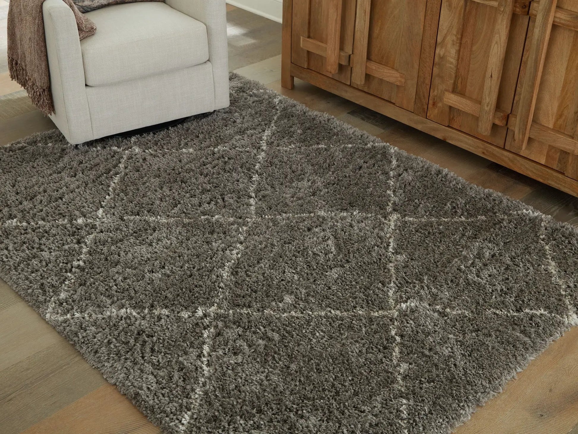 Wrenlow area rug, plush gray shag pile in living room beside beige sofa and wooden cabinet on Tampa Home & Garden Store