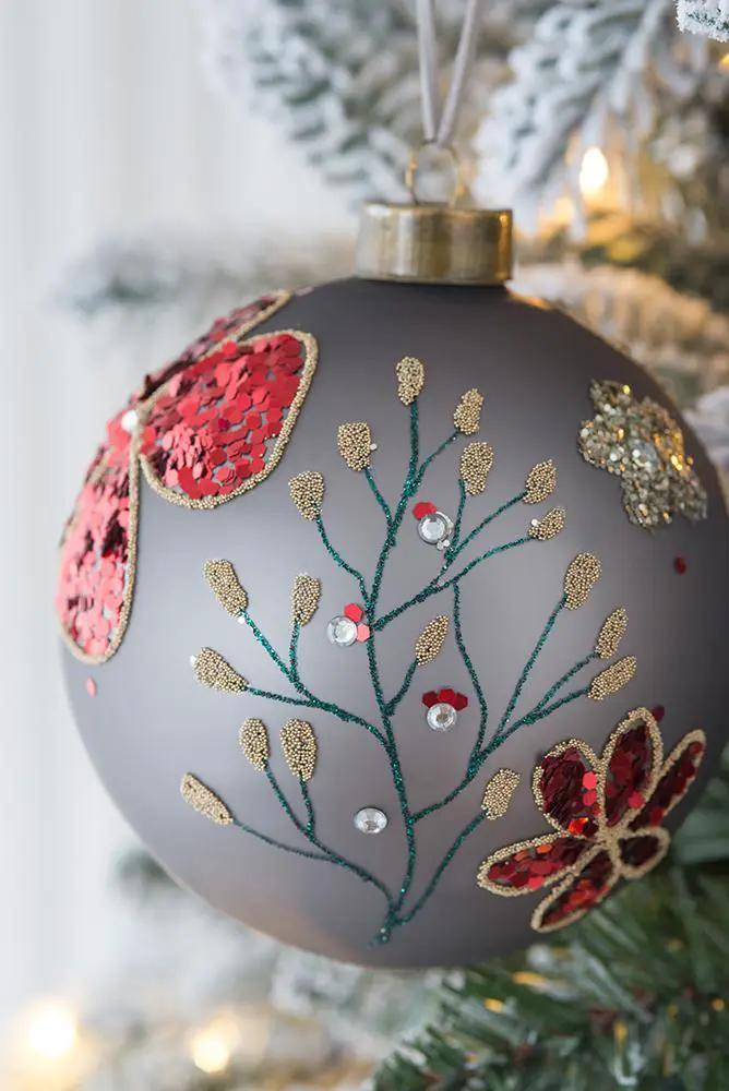 Glass gray Christmas ball ornament with red sequin patches, green branches and gold accents on Tampa Home & Garden Store