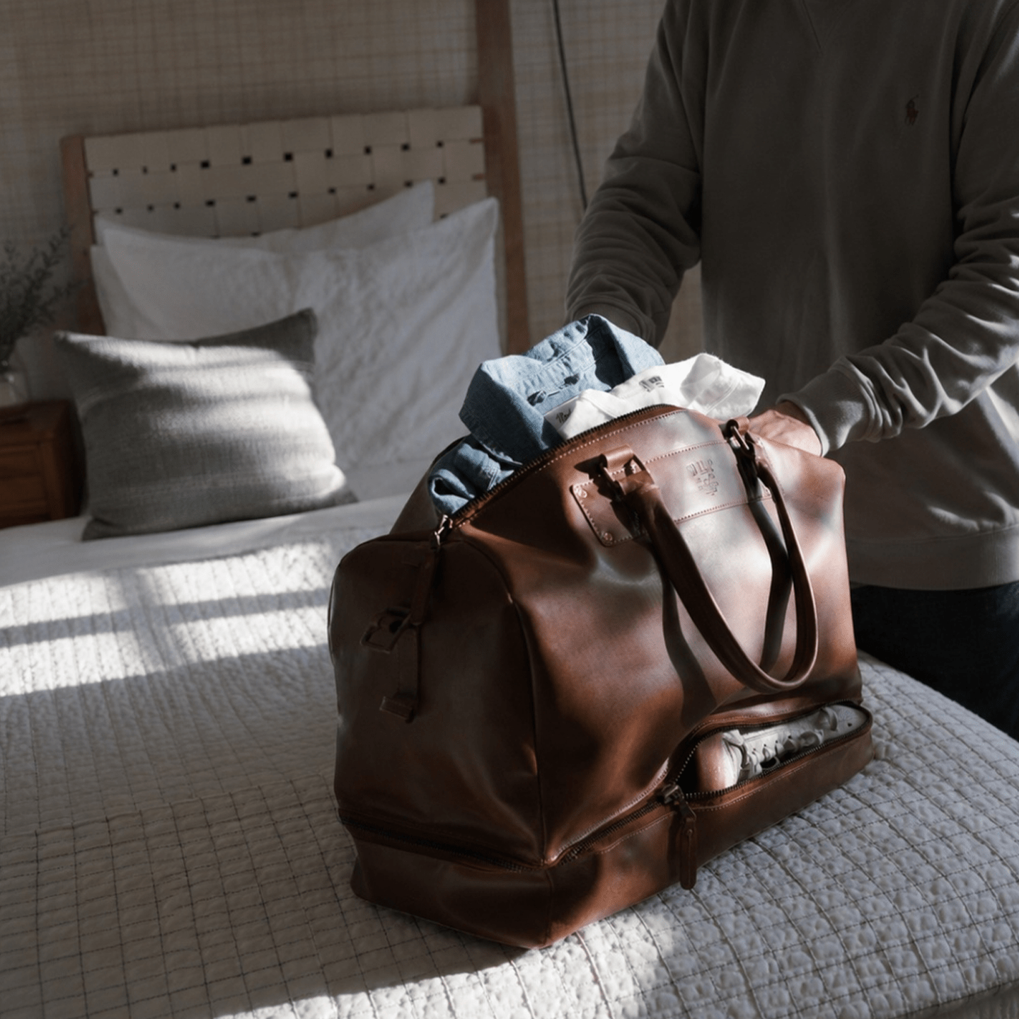 The Field Duffle by Will Leather Goods brown leather duffel bag being packed with clothes on bed on Tampa Home & Garden Store