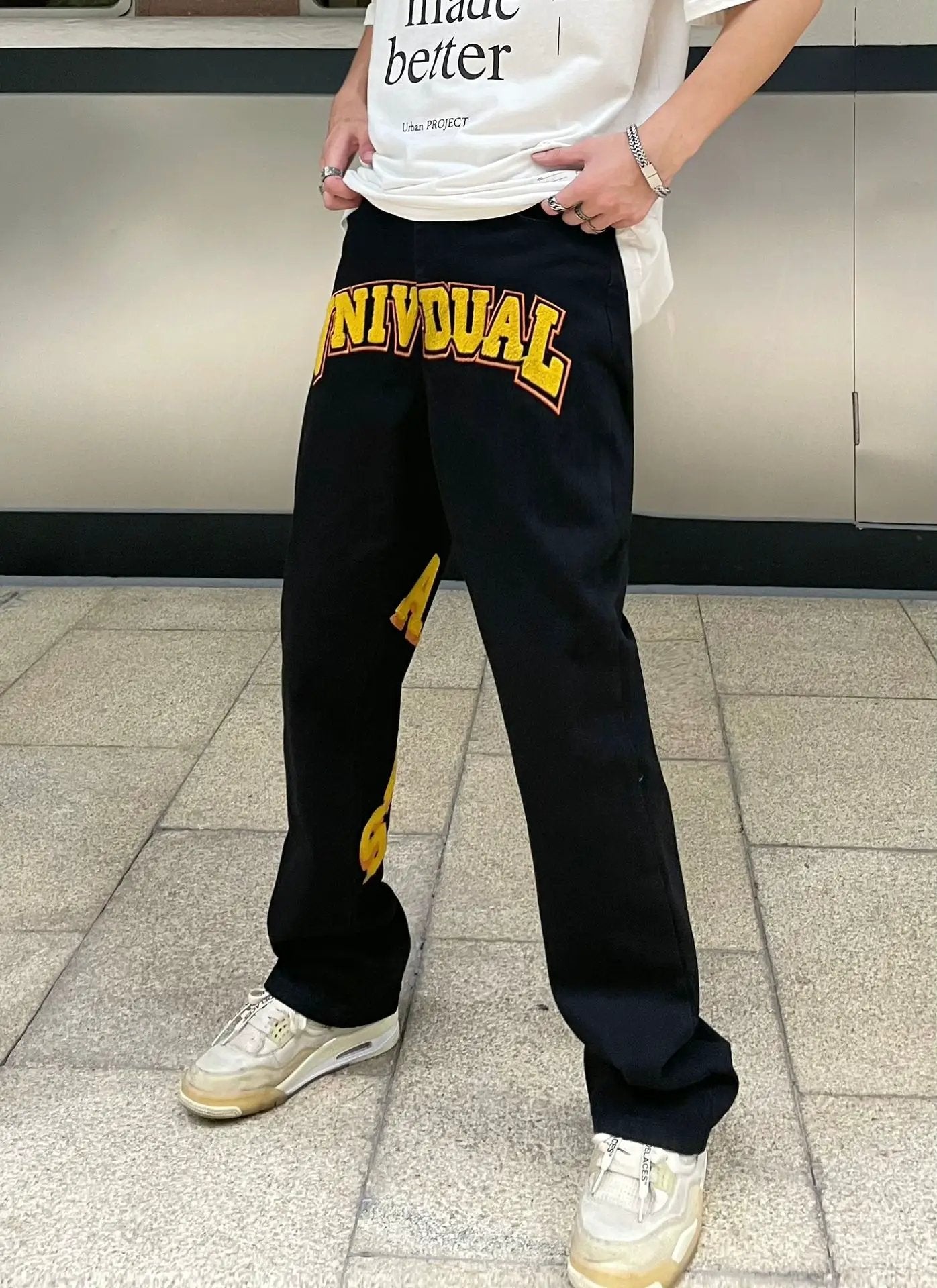 Unisex black street-fashion jeans with bold yellow INDIVIDUAL embroidery across thigh on Tampa Home & Garden Store