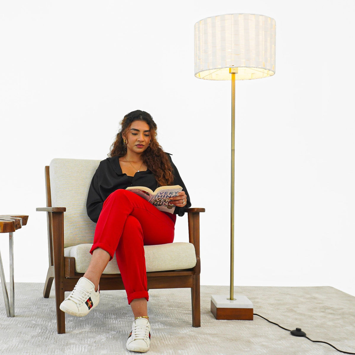Viora floor lamp in gold with white mosaic shade beside a seated woman reading a magazine on Tampa Home & Garden Store