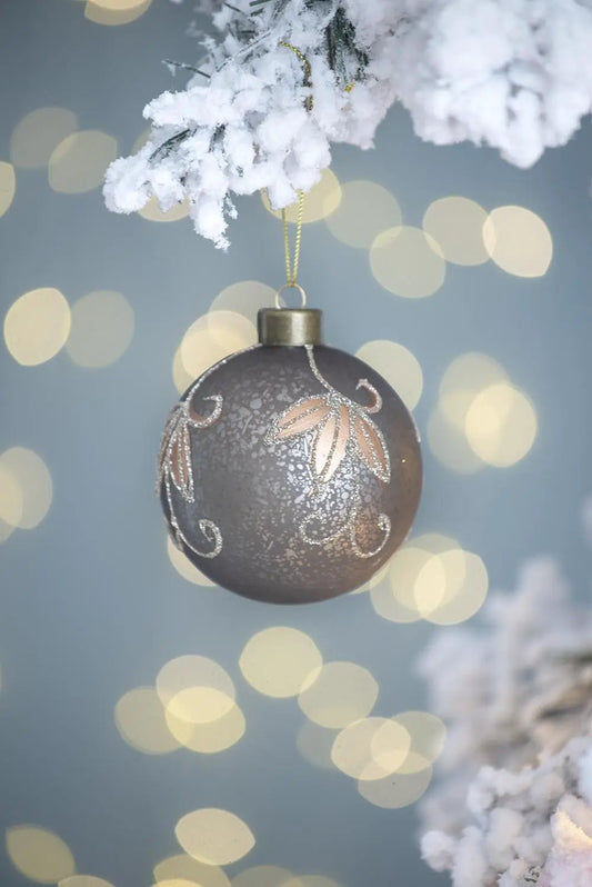 Christmas ball ornament hanging from a snow-covered branch, bronze with glittering floral motif on Tampa Home & Garden Store