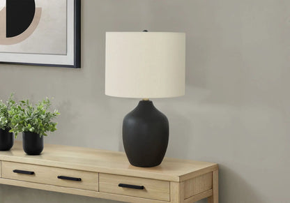 Table lamp with ceramic black base and cream shade on a light wood dresser on Tampa Home & Garden Store