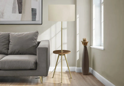 Floor lamp with brass tripod base and cream drum shade beside a gray sofa in living room on Tampa Home & Garden Store