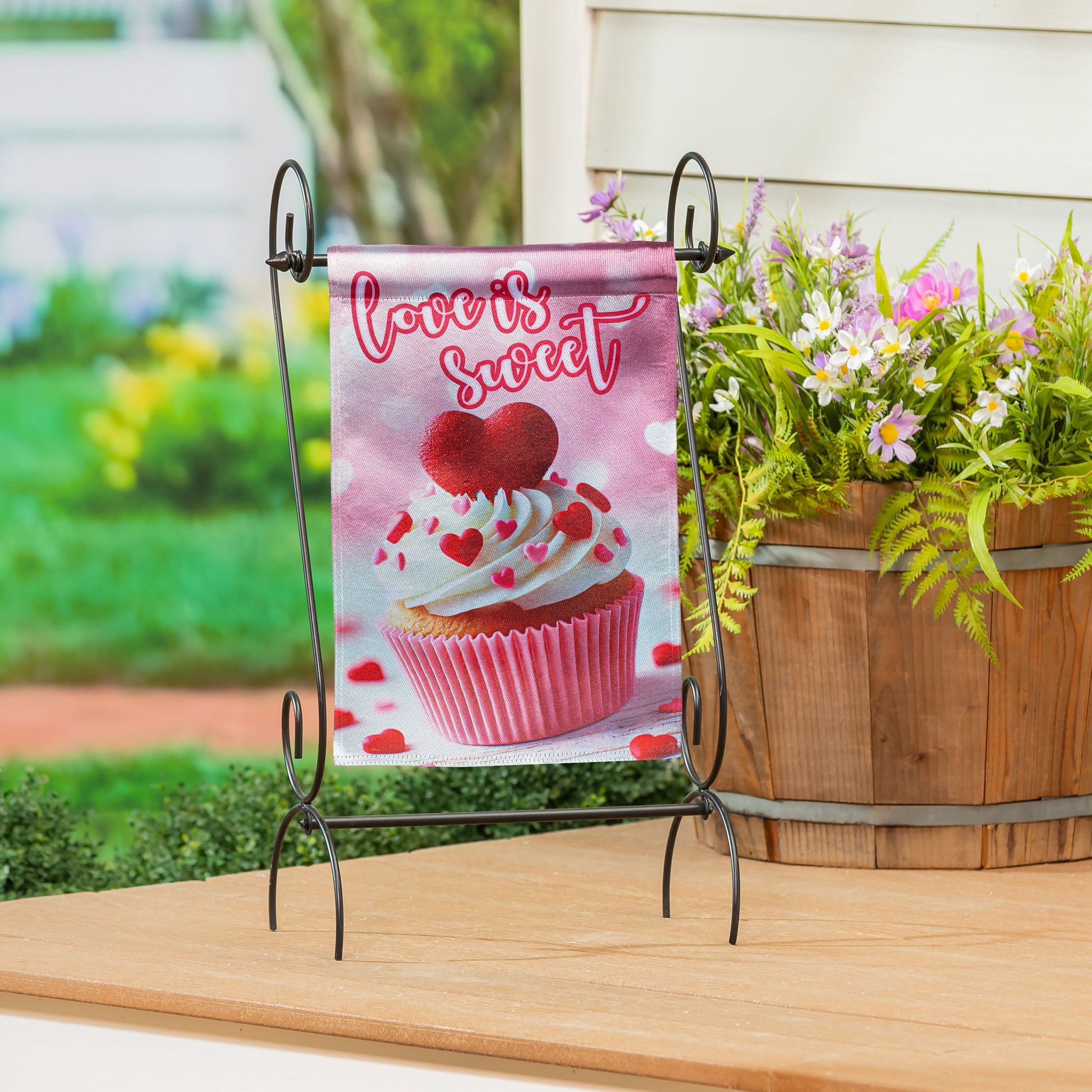 Cupcake Of Love Lustre Garden Flag pink with cupcake heart design on metal stand among flowers on Tampa Home & Garden Store