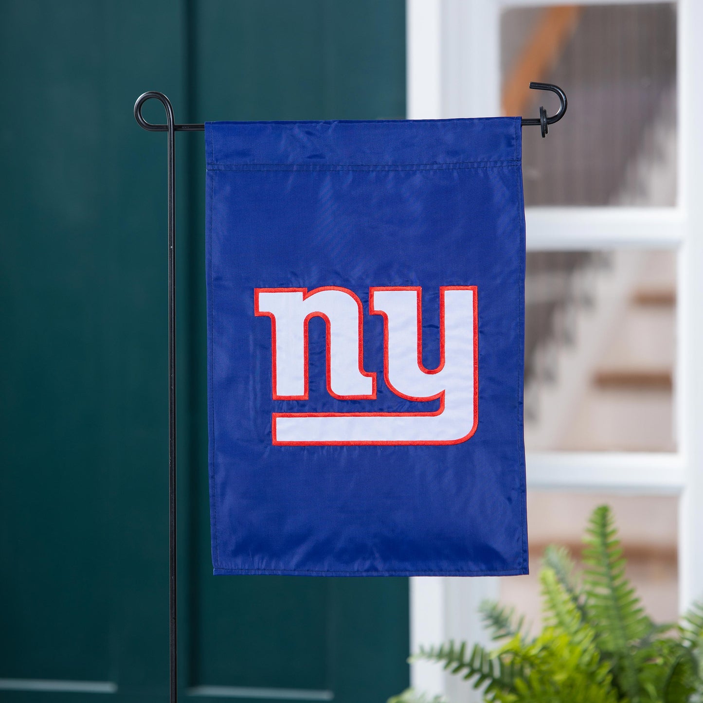 Applique flag blue New York Giants logo with red-outlined white letters on a black metal stand on Tampa Home & Garden Store