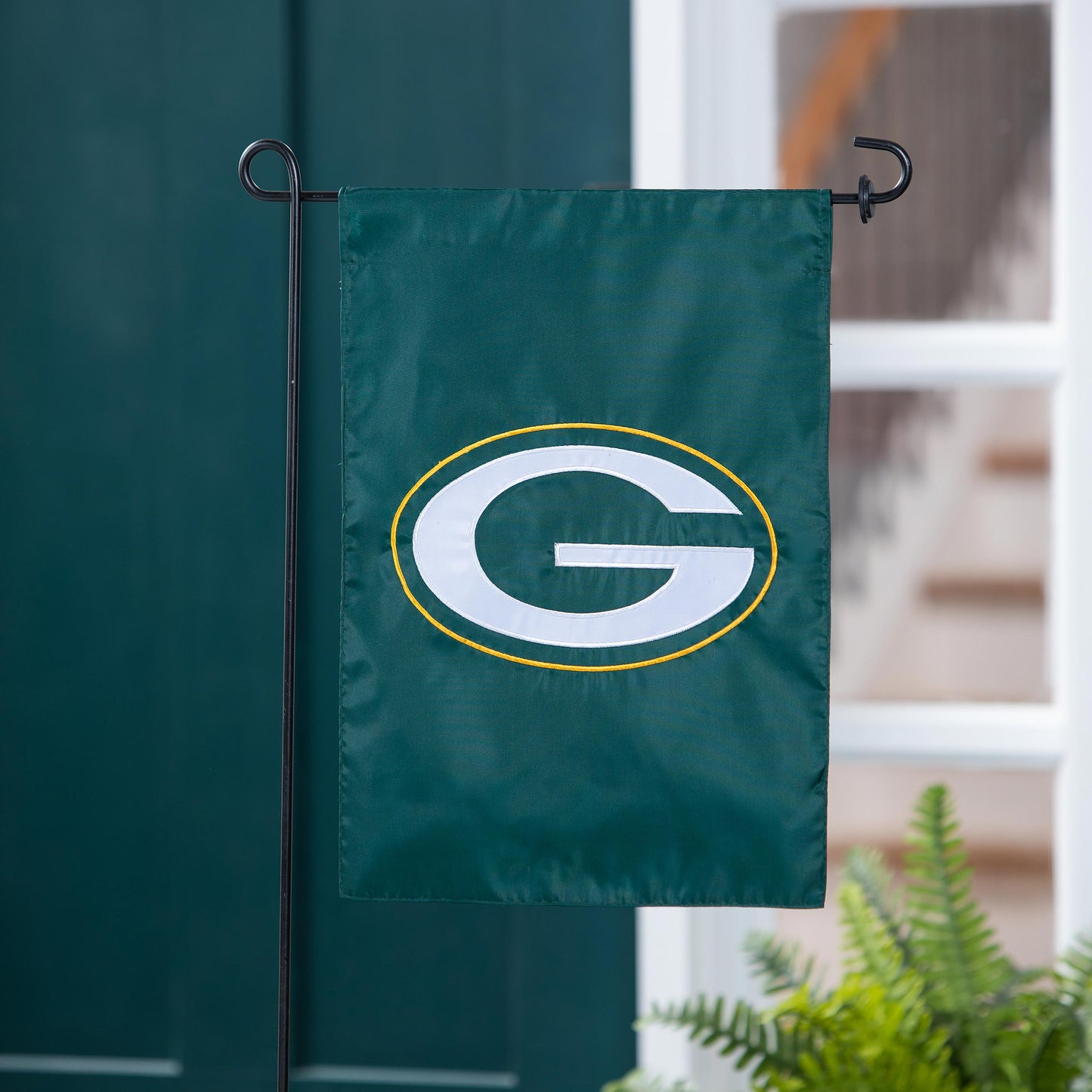 Green Bay Packers applique garden flag with white G and yellow ring on a black metal stand on Tampa Home & Garden Store