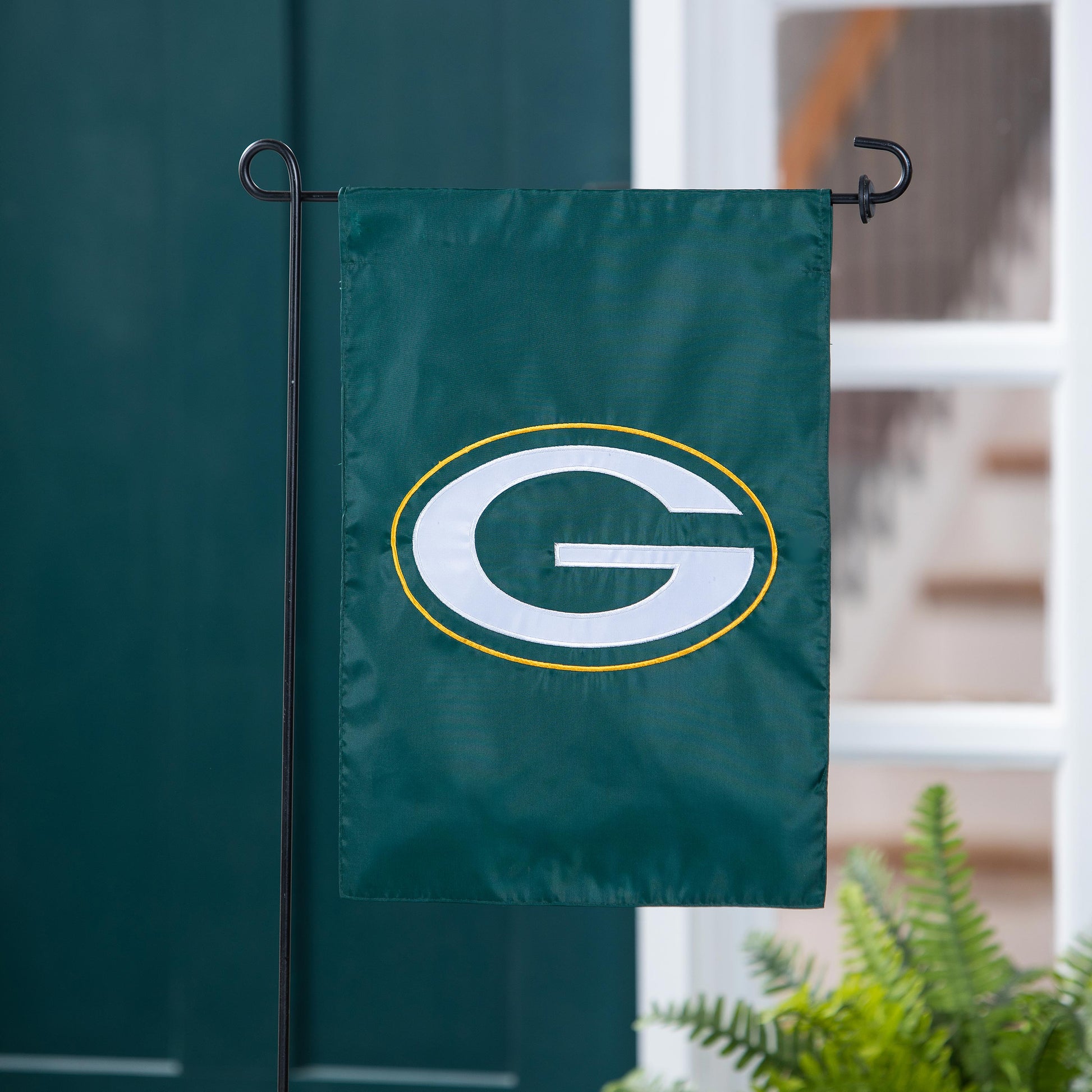 Green Bay Packers applique garden flag with white G and yellow ring on a black metal stand on Tampa Home & Garden Store