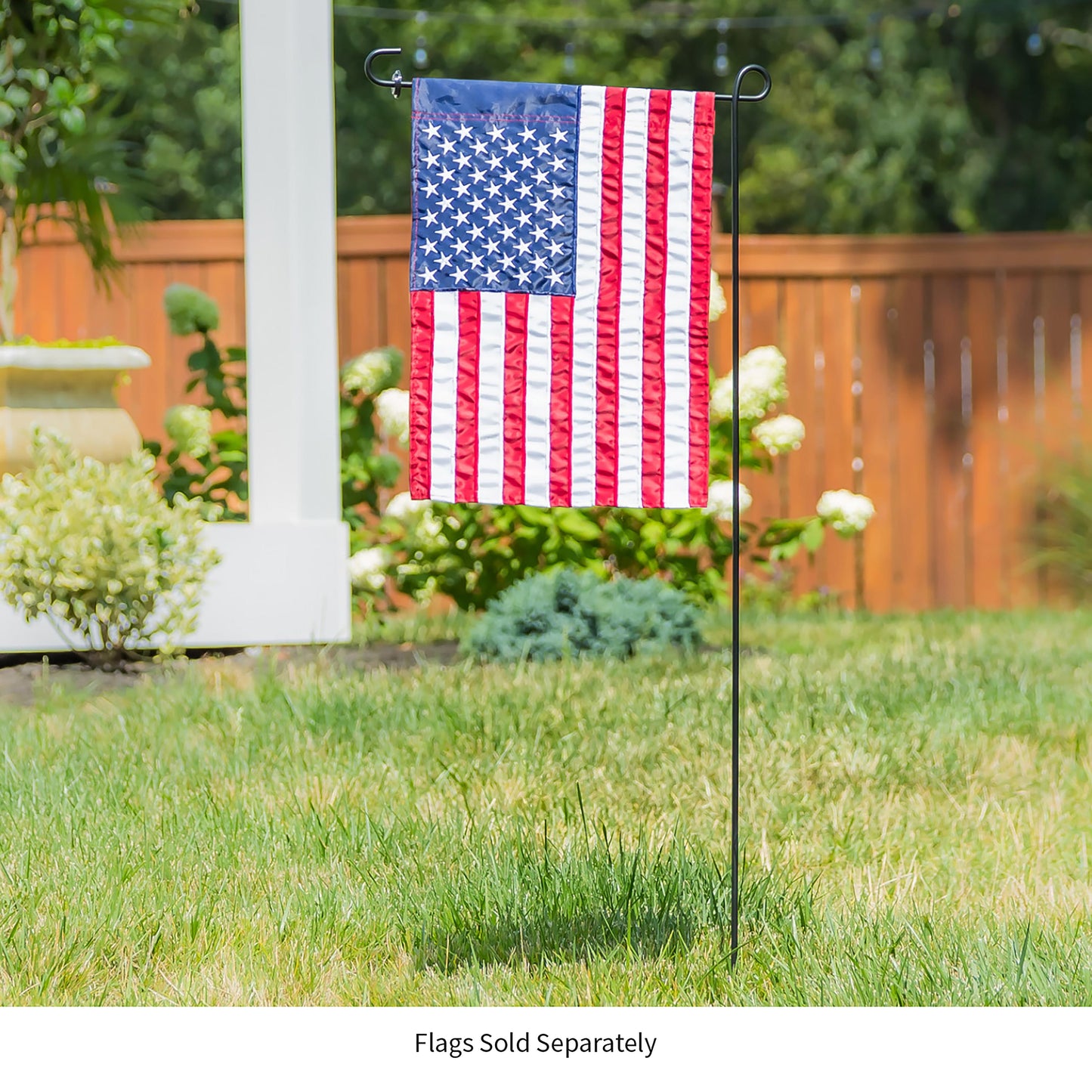 Black metal garden flag stand with curved top holding an American flag on a lawn on Tampa Home & Garden Store