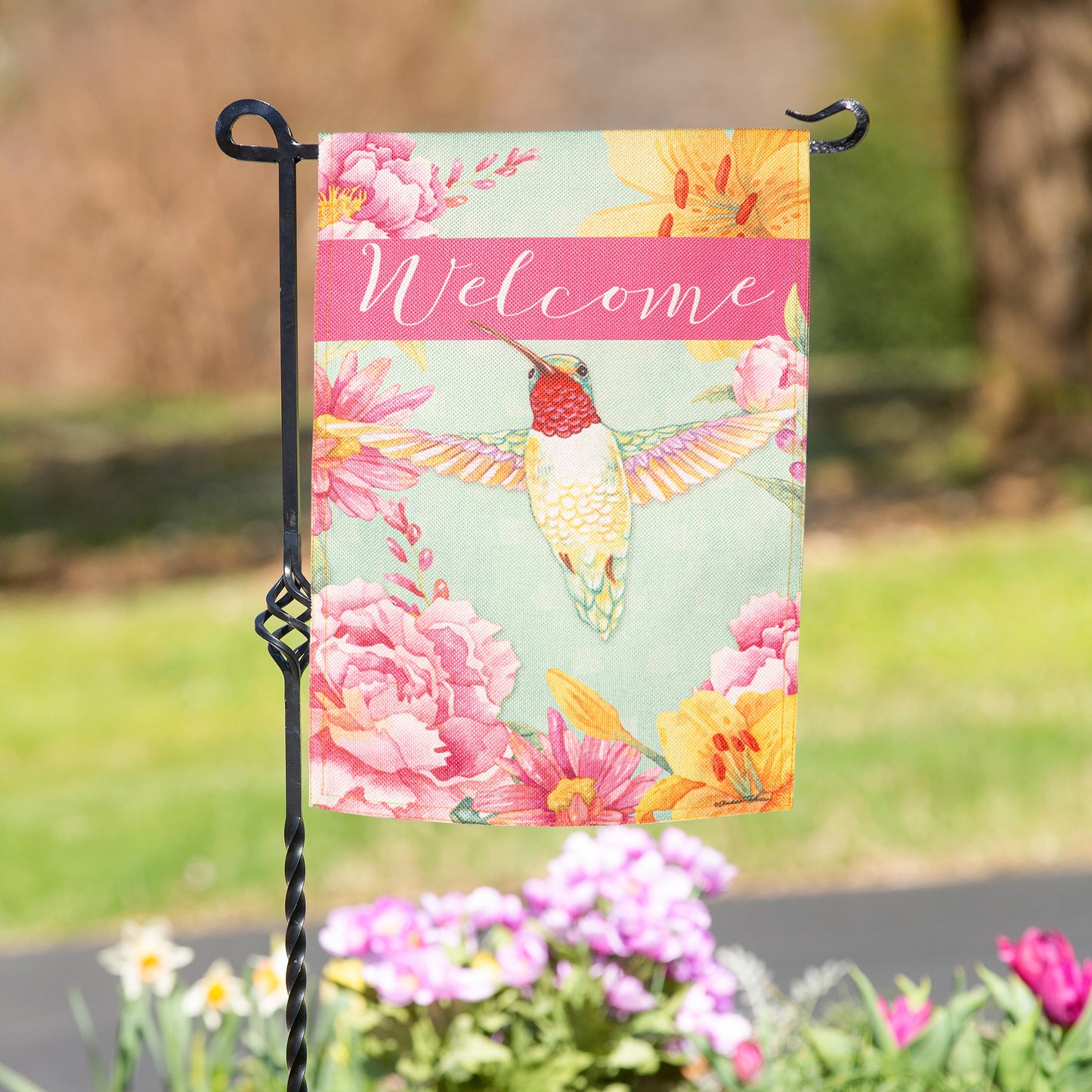 Welcome Hummingbird Burlap Garden Flag by Evergreen with pink florals on a black twisted stake on Tampa Home & Garden Store