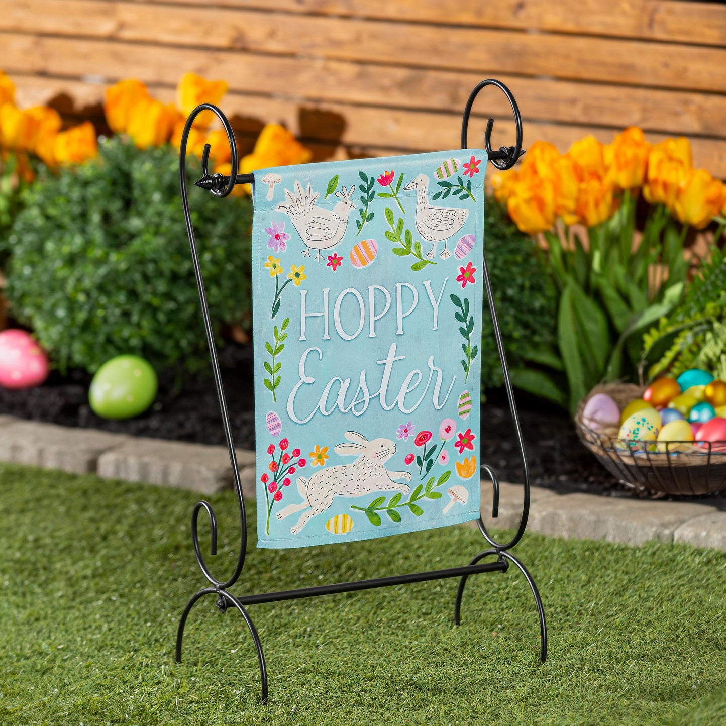 In Bloom Suede Garden Flag turquoise Easter design with bunnies and birds on a black metal stand on Tampa Home & Garden Store