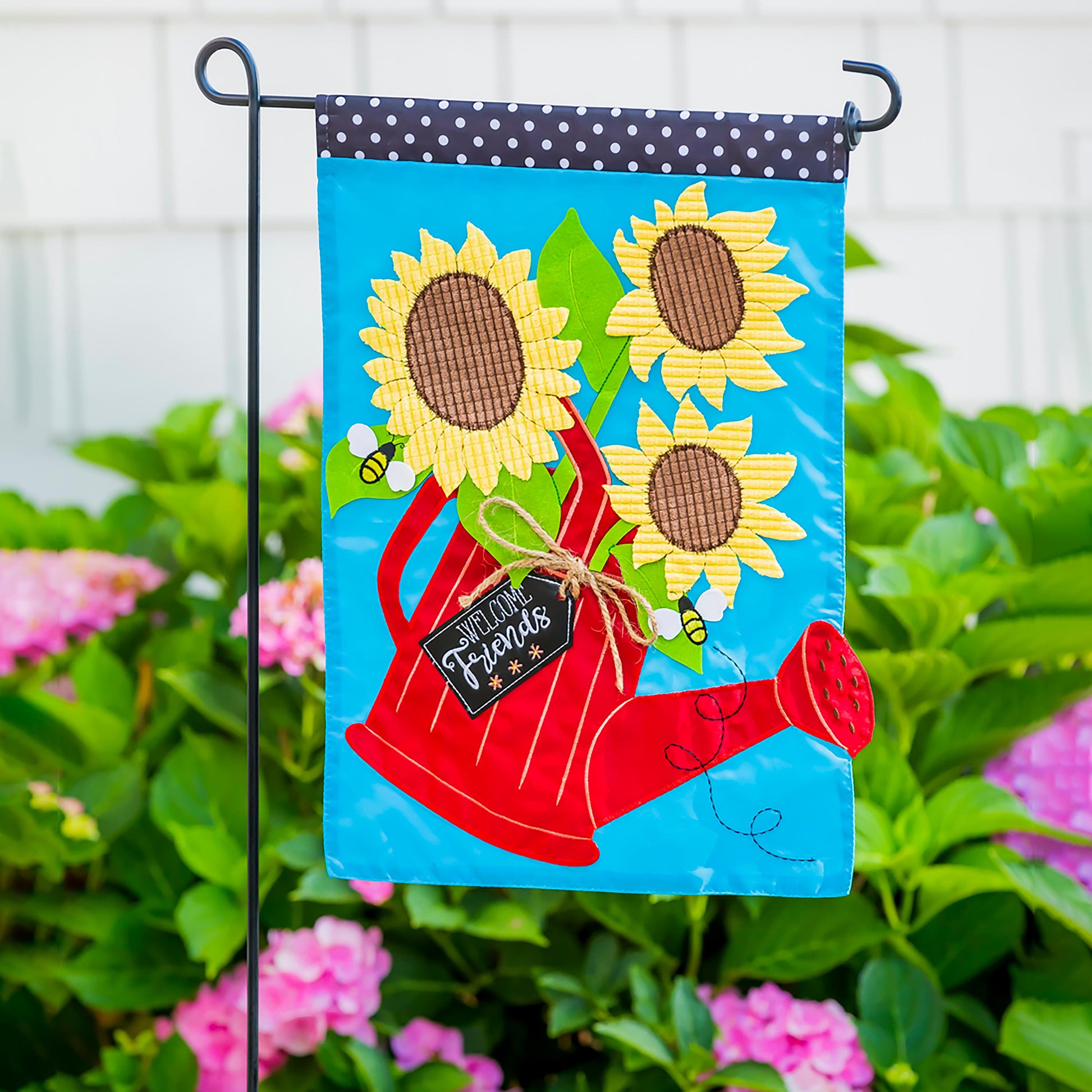Black metal flag stand with blue sunflower flag and navy polka-dot header on Tampa Home & Garden Store