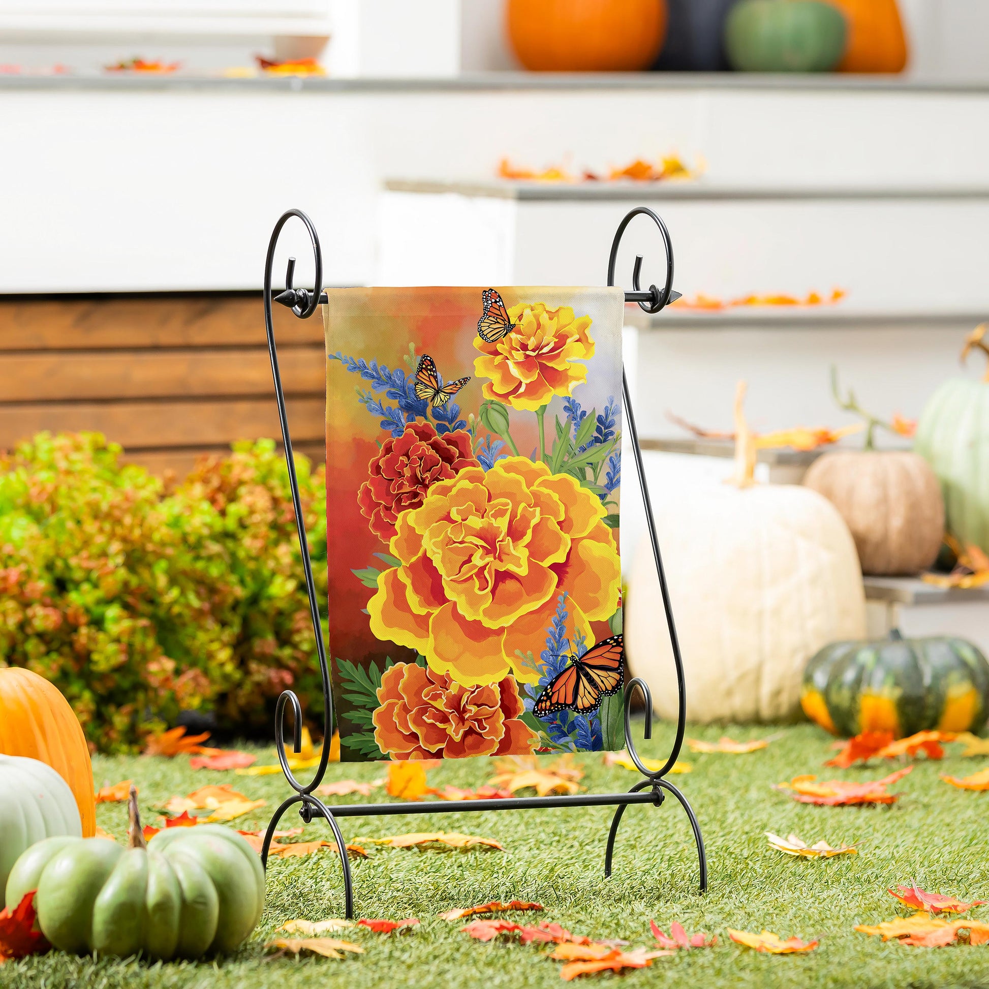 Mariposa Melody Burlap Garden Flag with orange flowers and butterflies on a black metal stand on Tampa Home & Garden Store