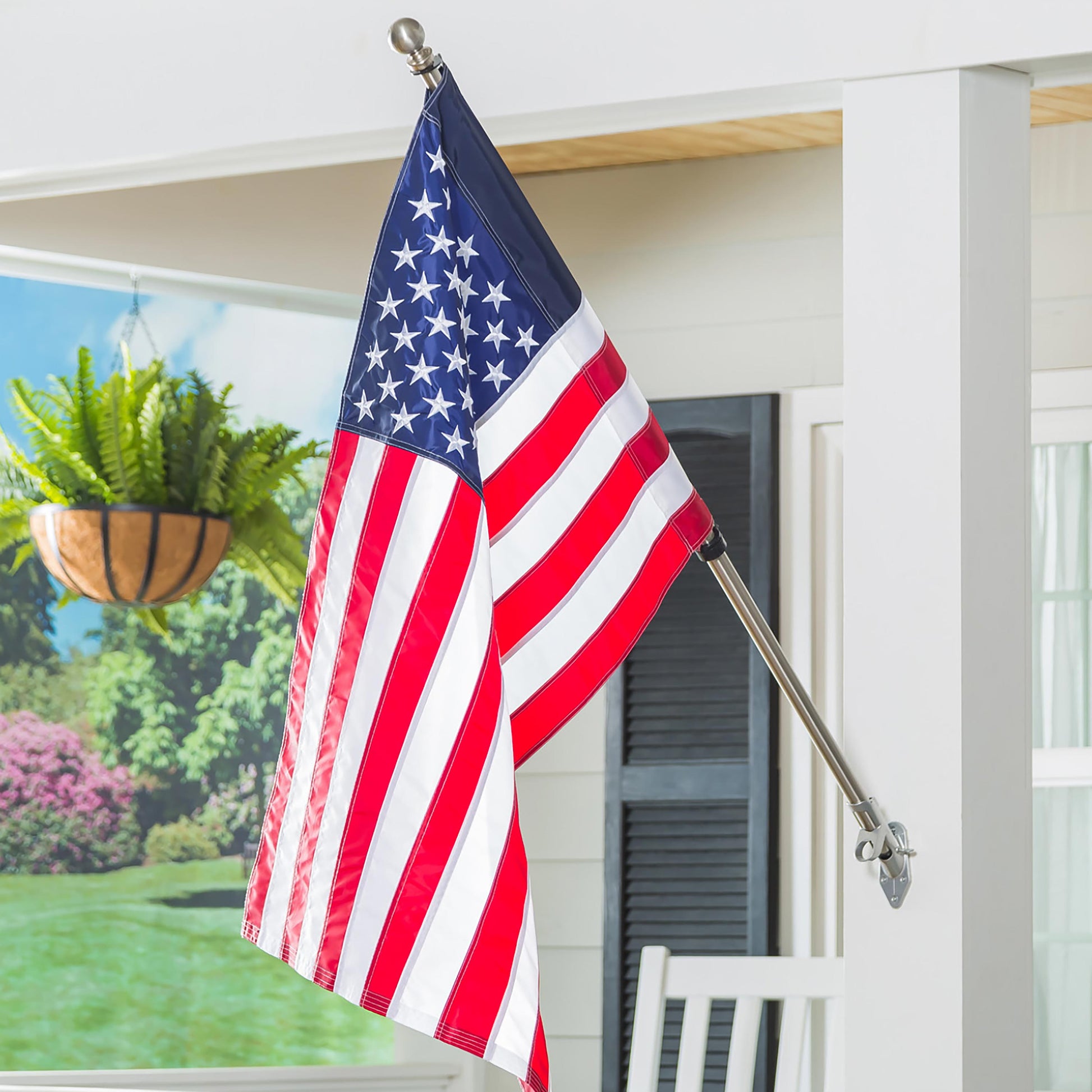 Extendable metal flag pole with silver finish displays an American flag on a white porch on Tampa Home & Garden Store