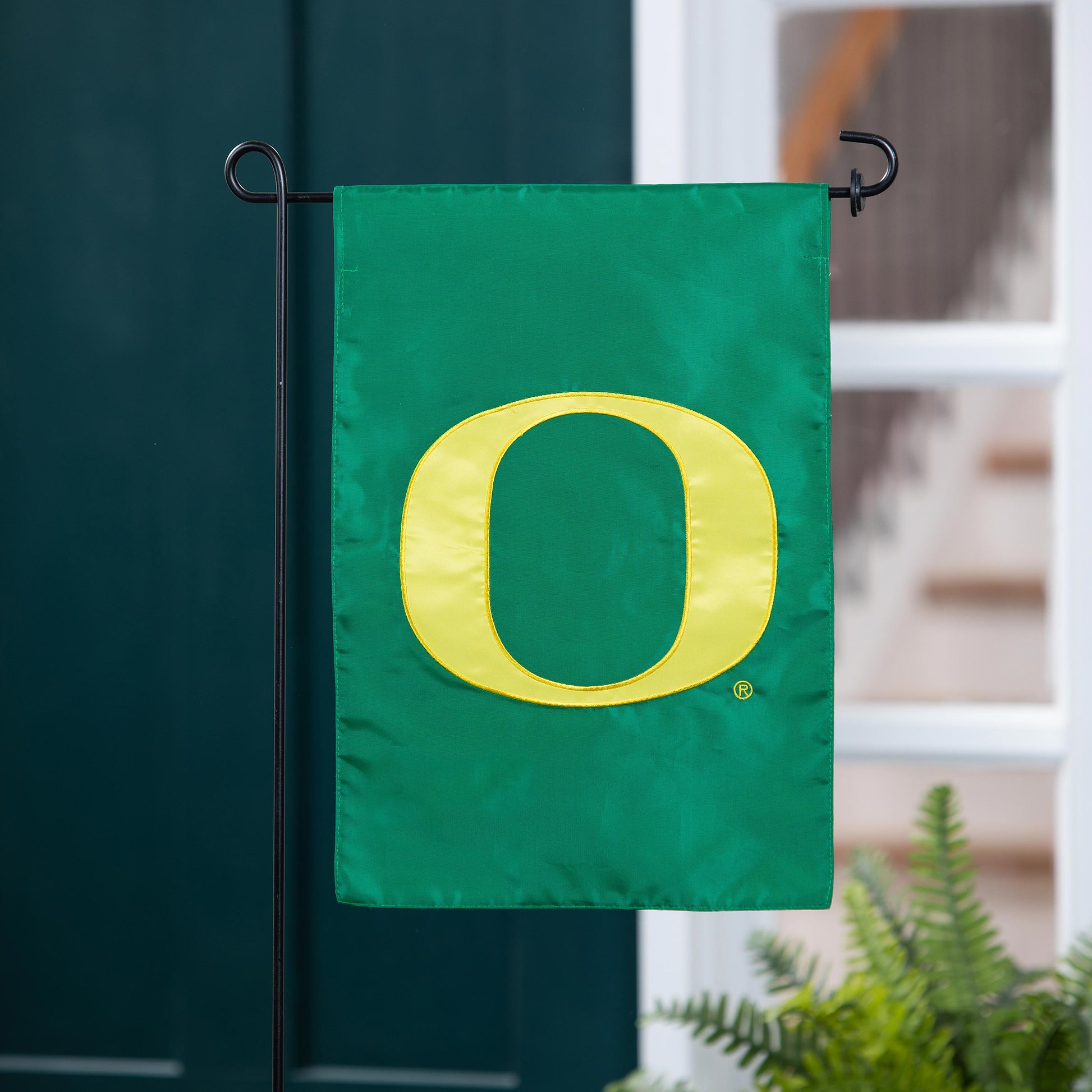 University of Oregon applique garden flag in green with a large yellow O on a black metal stand on Tampa Home & Garden Store