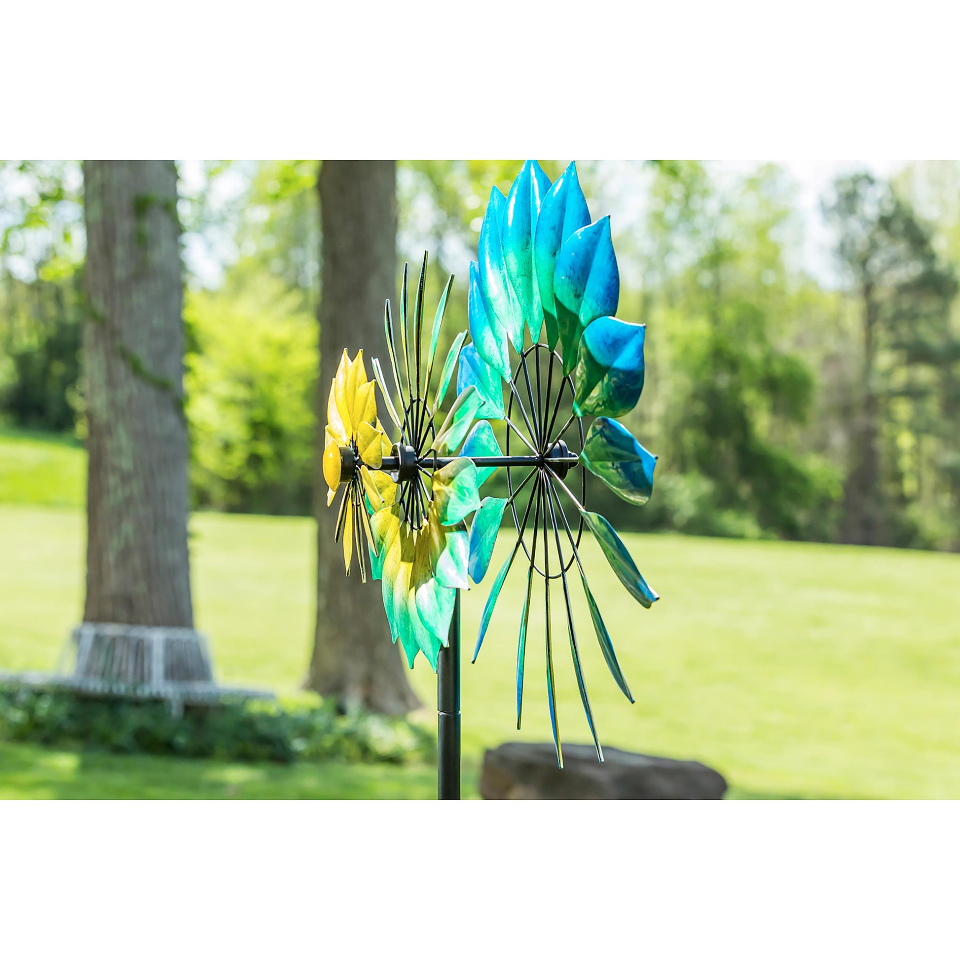 75H Wind Spinner Oceanic with blue teal blades and yellow tips in a sunlit garden on Tampa Home & Garden Store