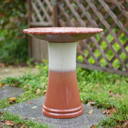 Handmade glazed ceramic bird bath on a terracotta pedestal with a red dish in a garden on Tampa Home & Garden Store
