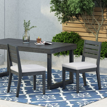 Outdoor armless dining chairs with white cushions around a dark wood table set on Tampa Home & Garden Store