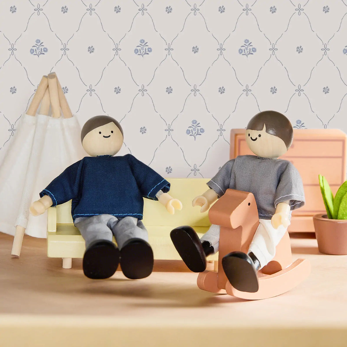 Tiny Land Sweetwood Dollhouse Dolls; two wooden dolls in blue and gray on a yellow sofa on Tampa Home & Garden Store