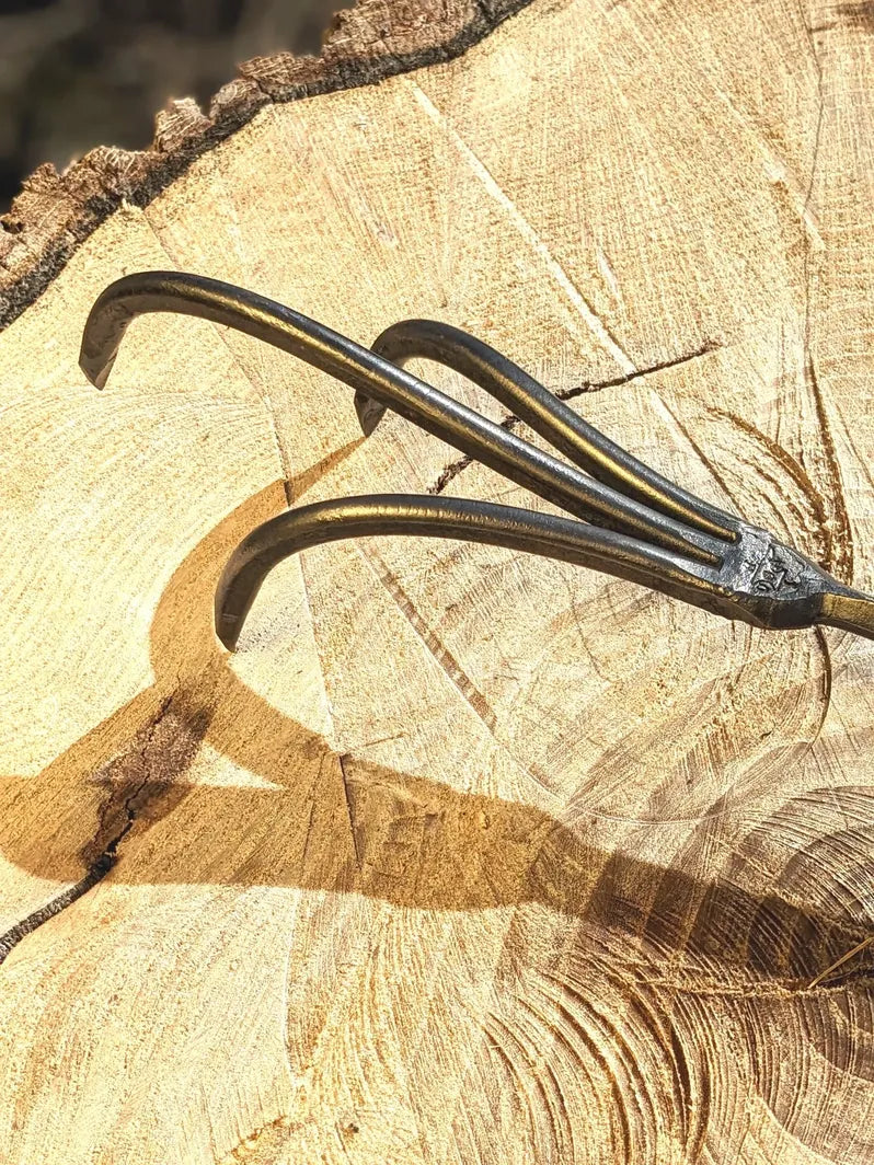 3-tine hand-forged cultivator by Homestead Iron, LLC on a split log on Tampa Home & Garden Store