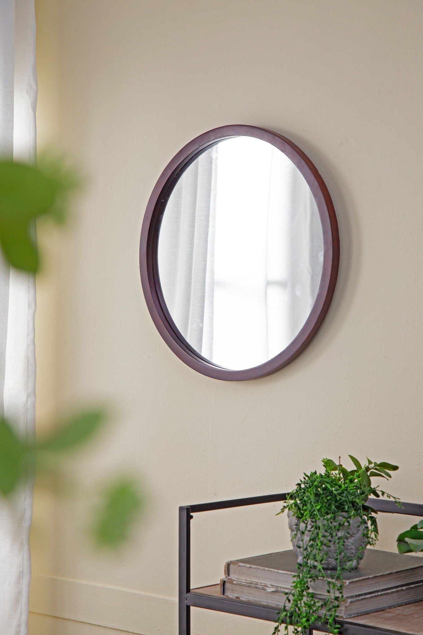Circle wall mirror with reddish-brown wooden frame on beige living room wall on Tampa Home & Garden Store