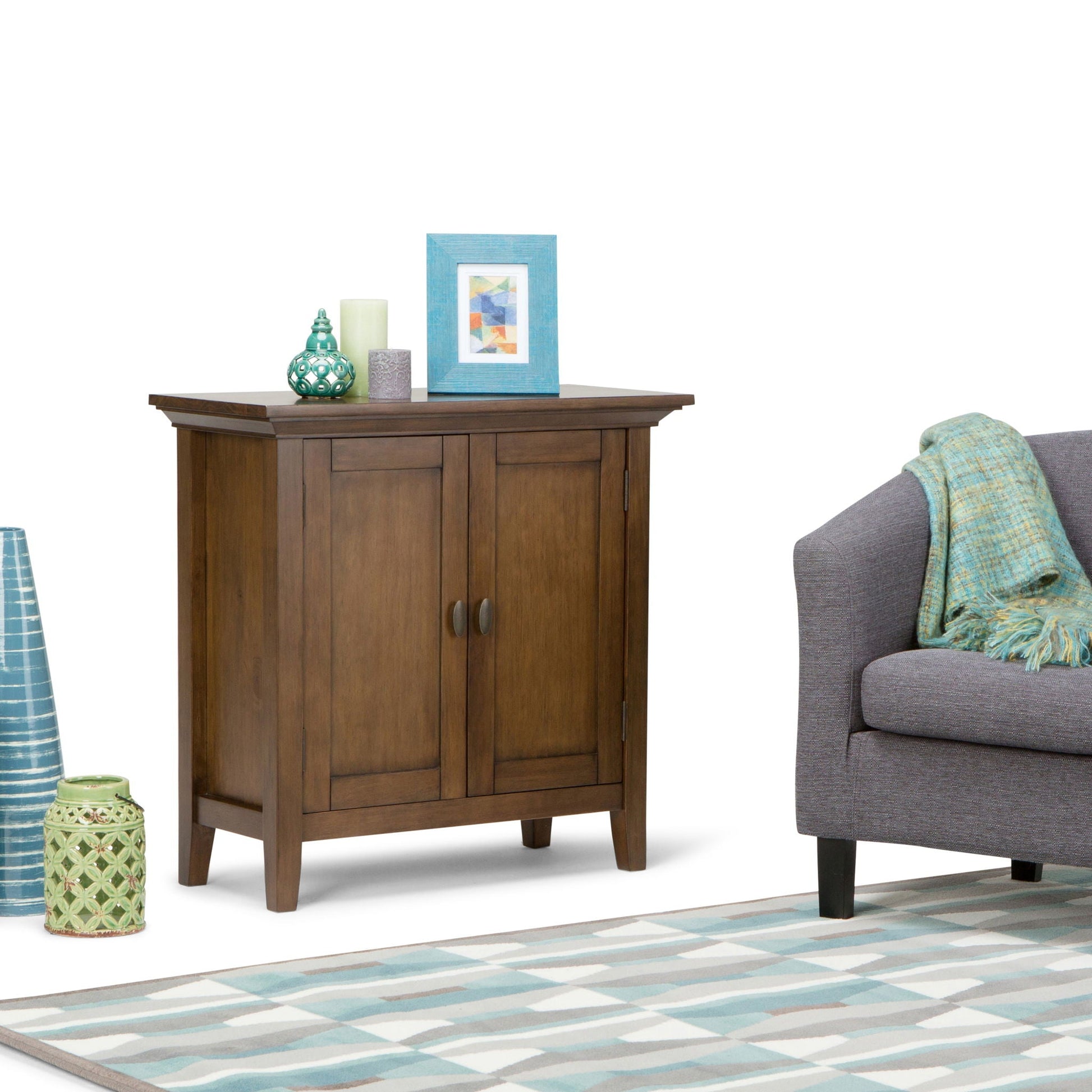 Redmond low storage cabinet in warm brown wood with turquoise frame, teal vase, two candles on Tampa Home & Garden Store