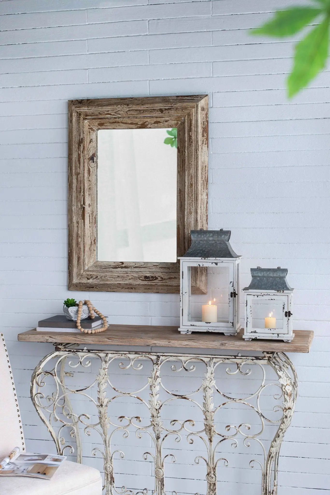 White hurricane lanterns (2) with candles on a rustic table beside a distressed wooden mirror frame on Tampa Home & Garden Store