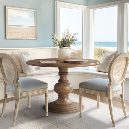 Walnut round pedestal table with diamond veneer top, beige cane-back chairs in a dining room on Tampa Home & Garden Store