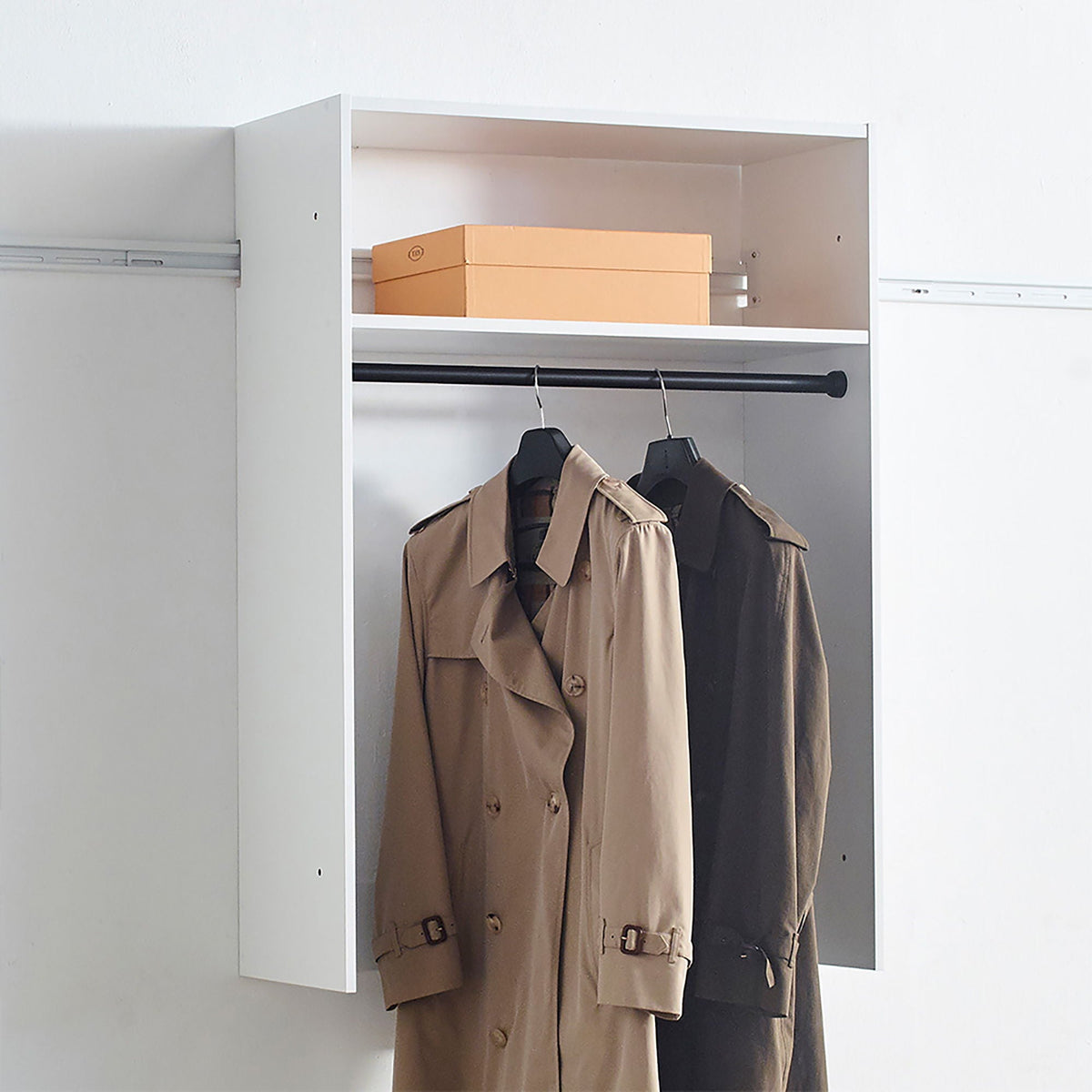 Wall mounted wood closet system with modular white frame and hanging rod, tan trench coat on Tampa Home & Garden Store