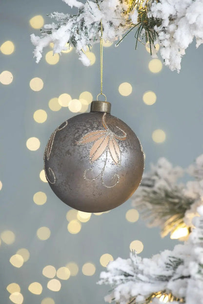 Christmas ball ornament, silver with glitter leaf design, hanging from snowy pine on Tampa Home & Garden Store