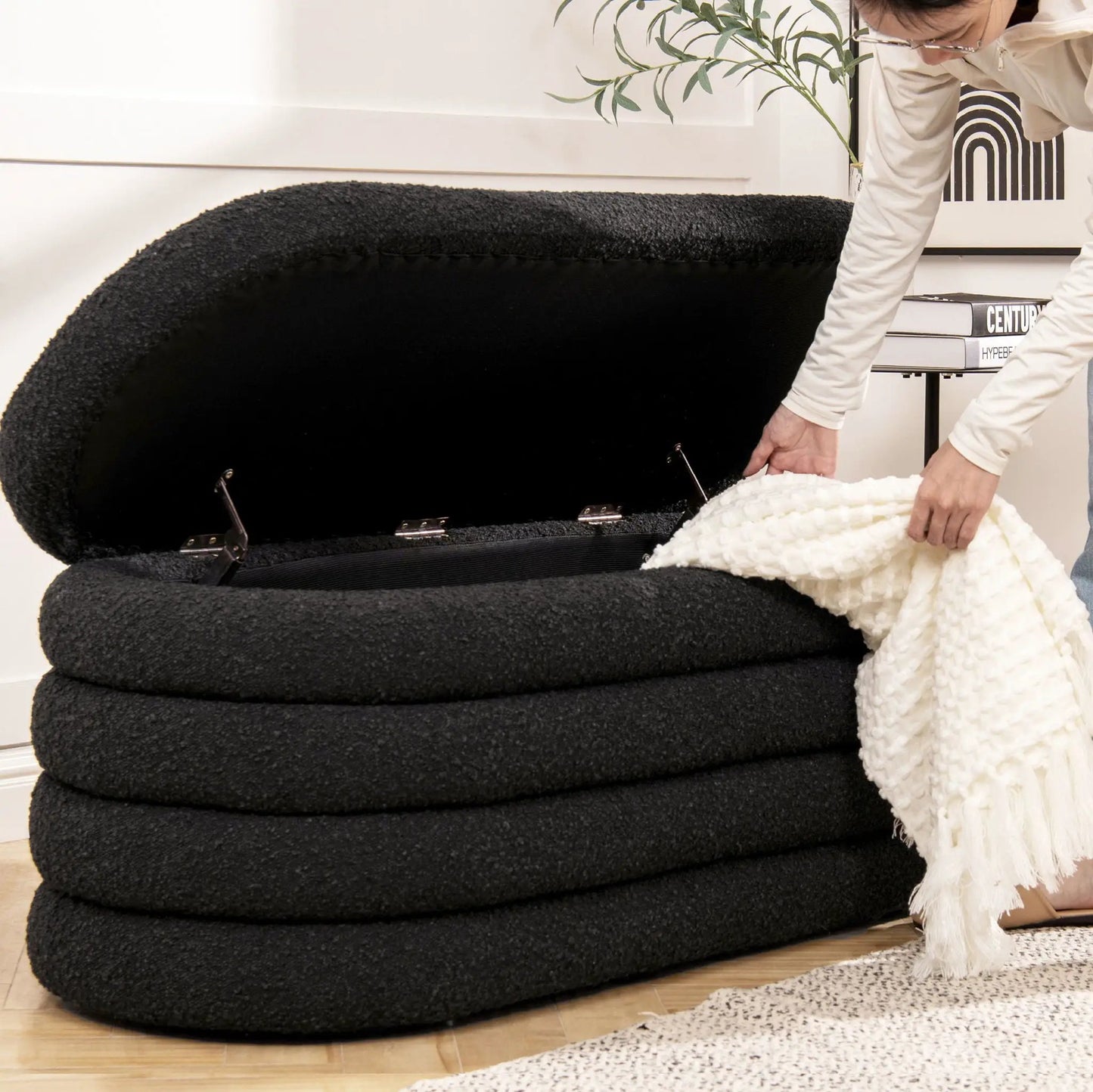 Fuji Upholstered Oval Storage Bench in black textured fabric; person near a white blanket on Tampa Home & Garden Store