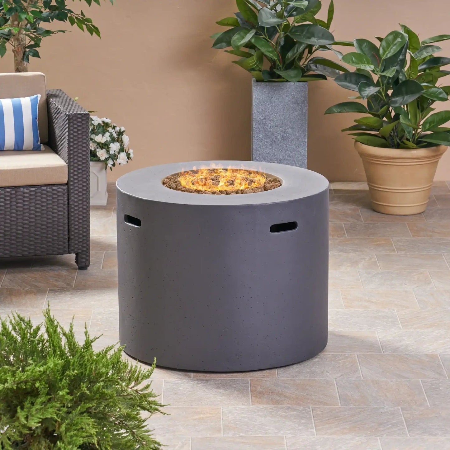 Round iron fire pit with 40,000 Btu flame and lava rocks on a patio with greenery on Tampa Home & Garden Store