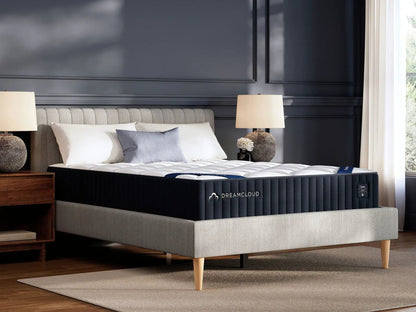 DreamCloud Classic Hybrid mattress on a gray upholstered platform bed with light wood legs in a dark paneled bedroom on Tampa Home & Garden Store