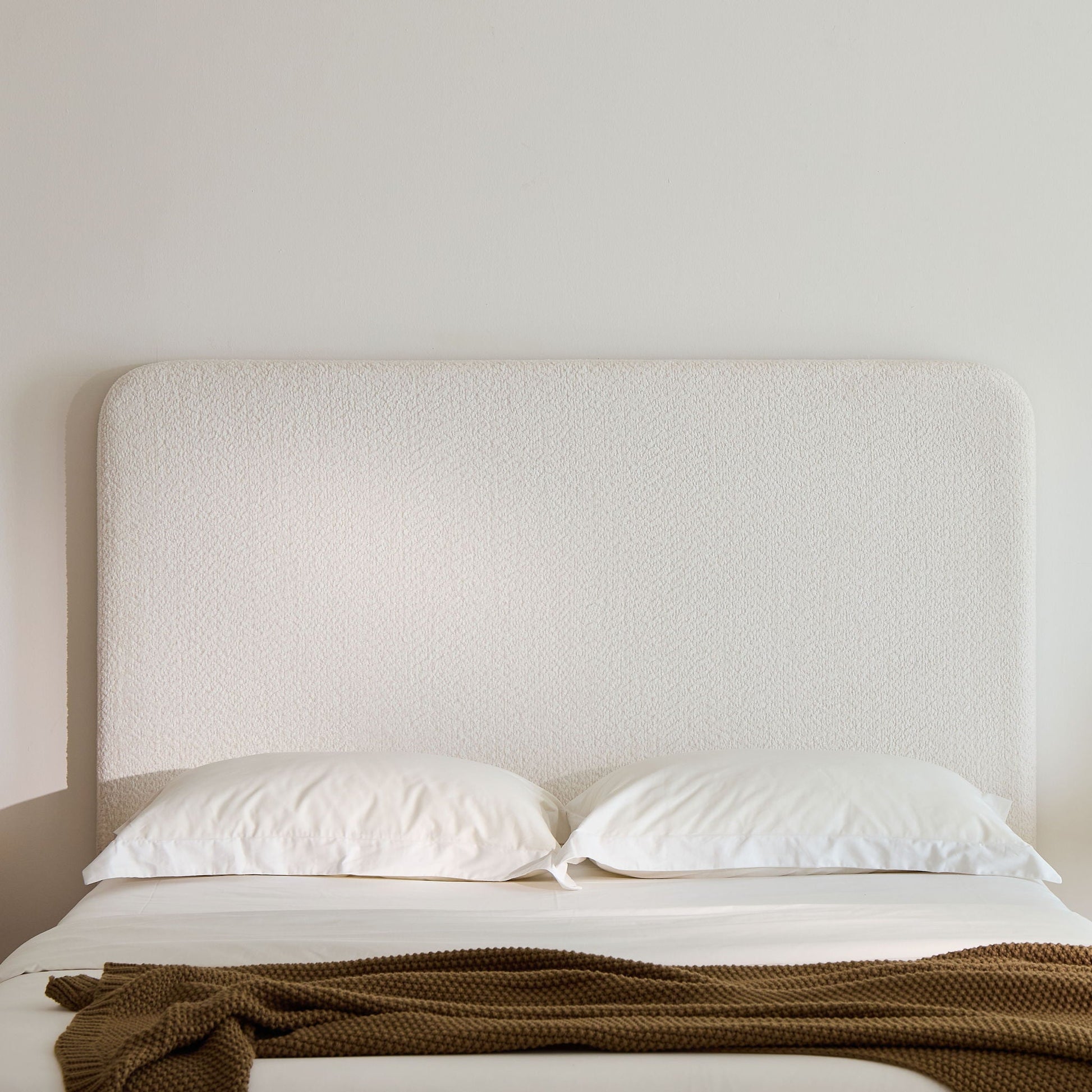 Canter tall headboard upholstered bed in cream fabric with white bedding and brown knit throw on Tampa Home & Garden Store