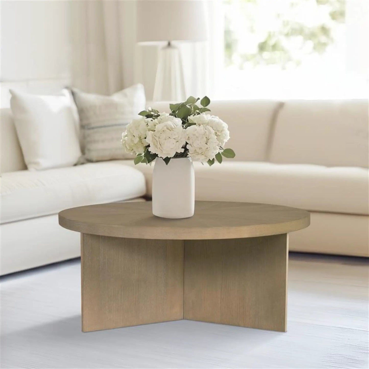 Round coffee table with solid veneer top in light wood, placed in a bright living room on Tampa Home & Garden Store
