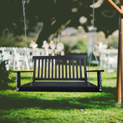 Black metal front porch swing with armrests on chains between wooden posts in a sunny yard on Tampa Home & Garden Store