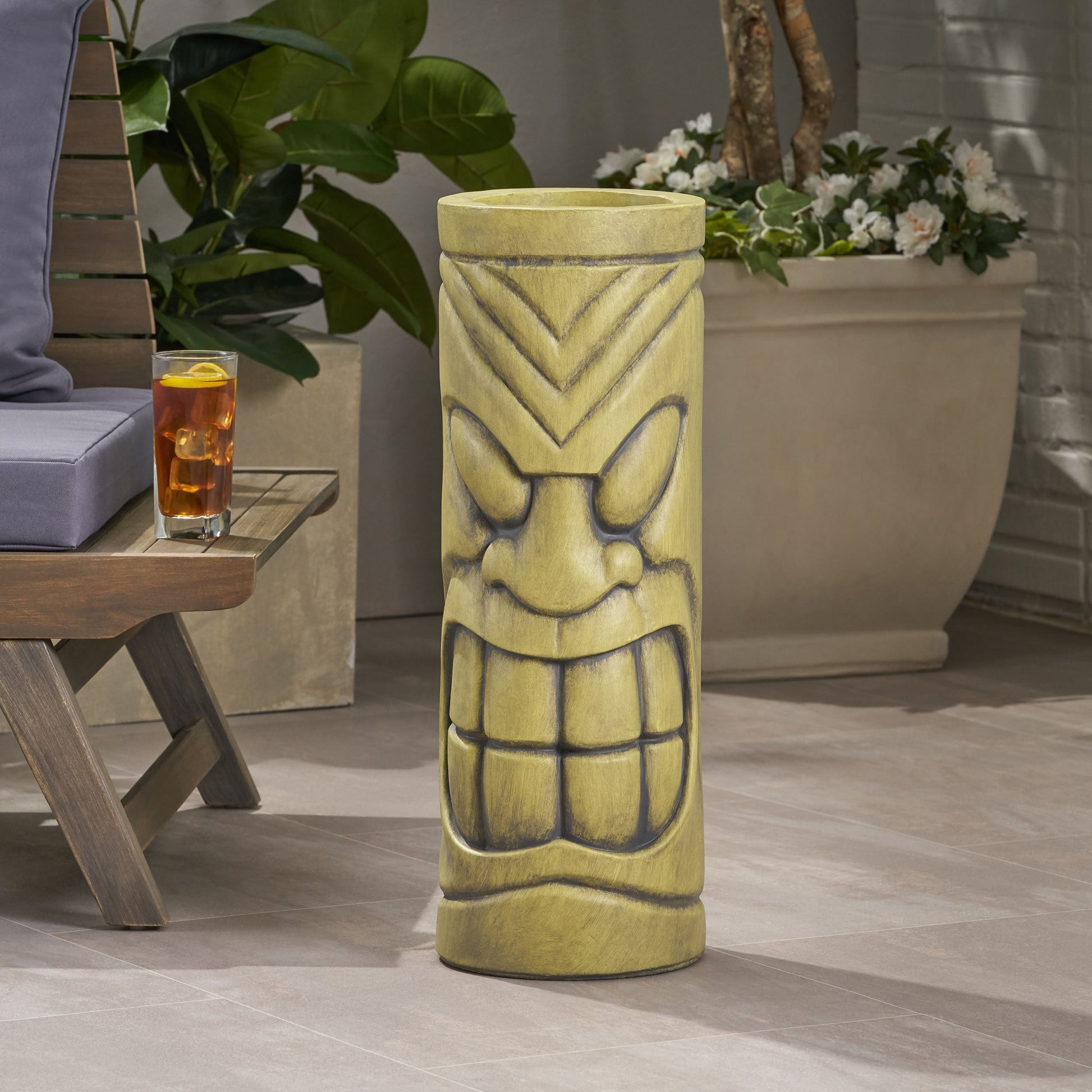 Stone statue urn planter with antique green finish and decorative face motif on a patio on Tampa Home & Garden Store
