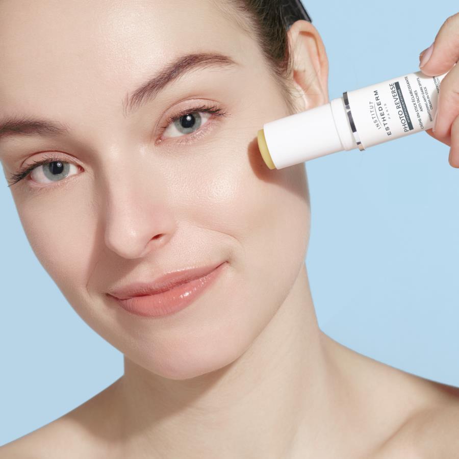 Esthederm Photo Reverse SPF50+ sunscreen stick with yellow applicator on cheek on Tampa Home & Garden Store