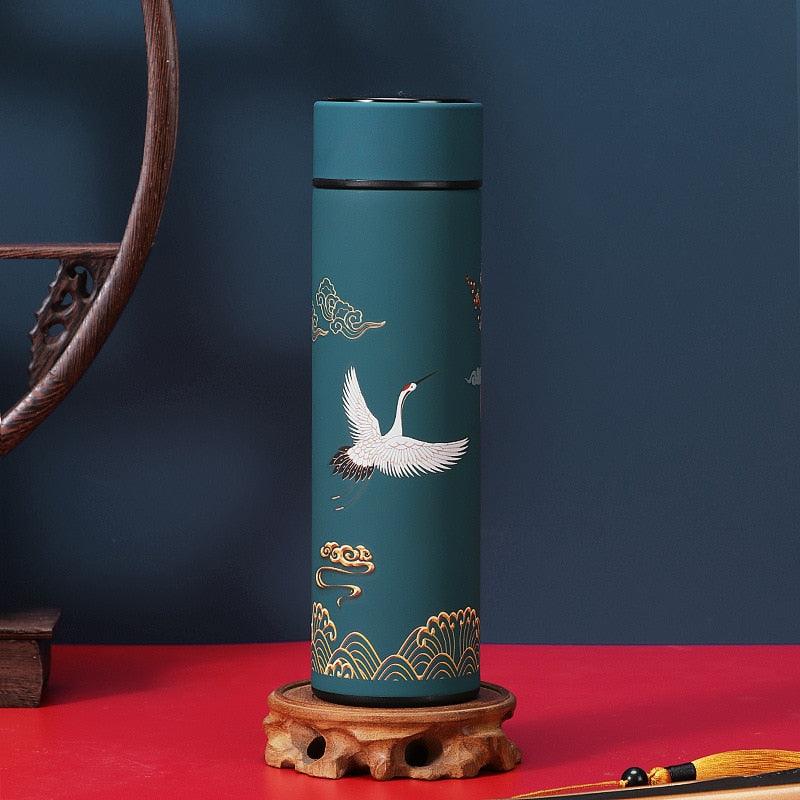 Teal stainless steel thermos bottle with white crane and gold wave motif, black lid on Tampa Home & Garden Store