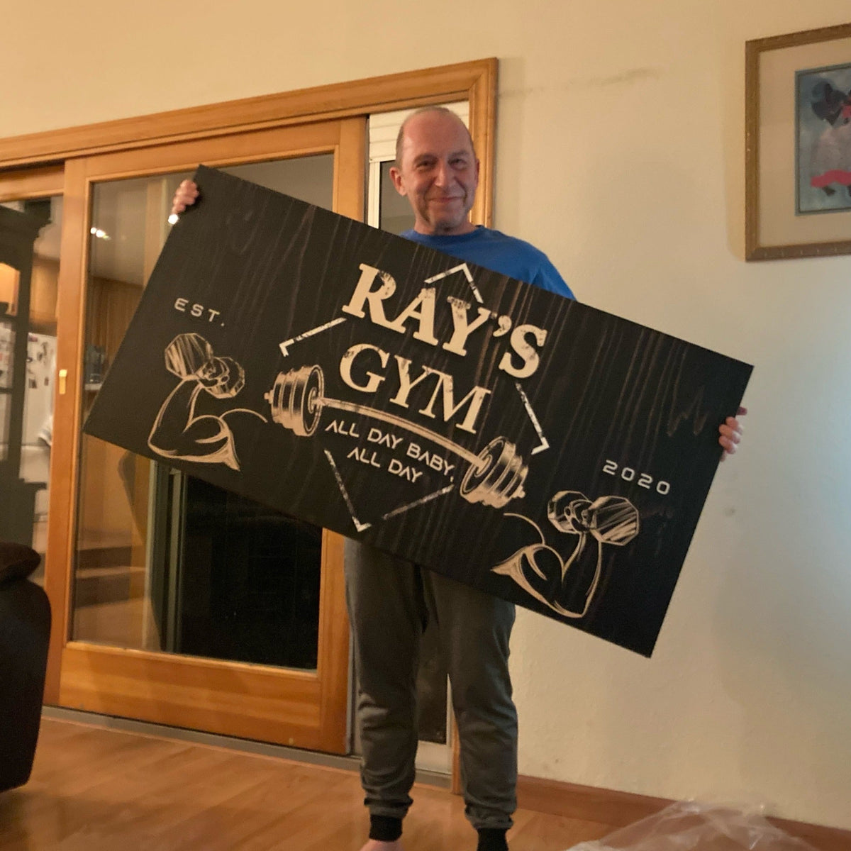 Gym Sign IV canvas by Tailored Canvases, black sign with white lettering held by a man on Tampa Home & Garden Store