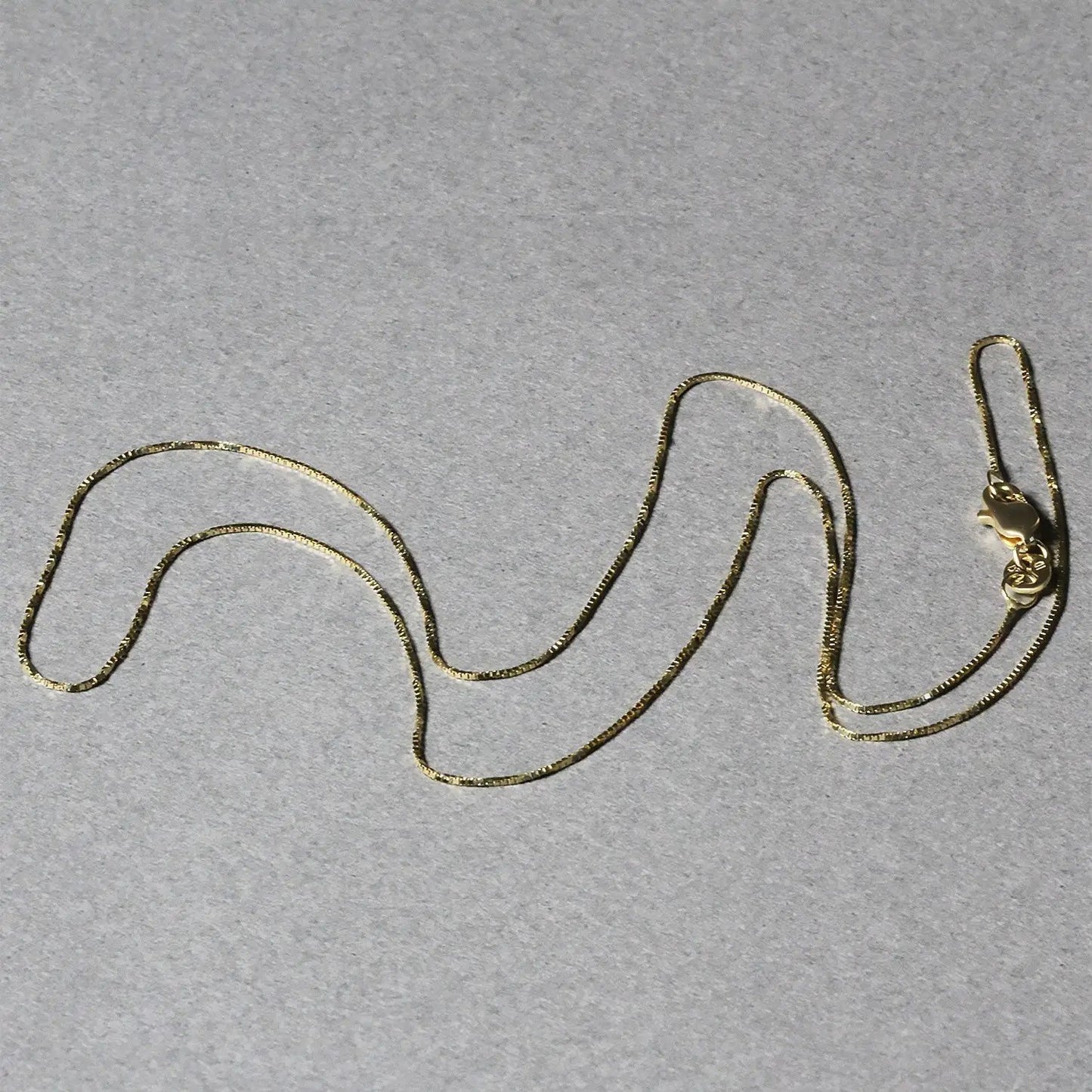 14k yellow gold box chain necklace 0.6mm by Bids.com with lobster clasp on gray background on Tampa Home & Garden Store