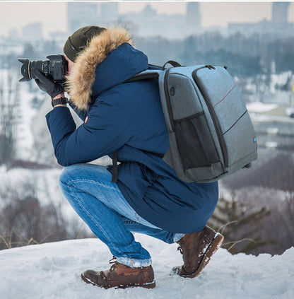 Camera backpack waterproof bag in gray worn by photographer kneeling in snow with camera on Tampa Home & Garden Store