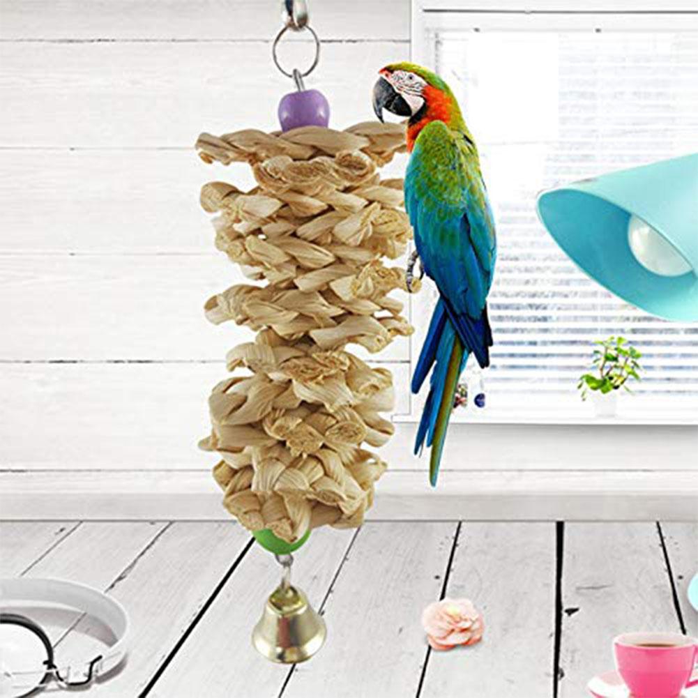 Parrot toy with bell and natural wooden grass bite hanging cage, colorful macaw perched beside on Tampa Home & Garden Store