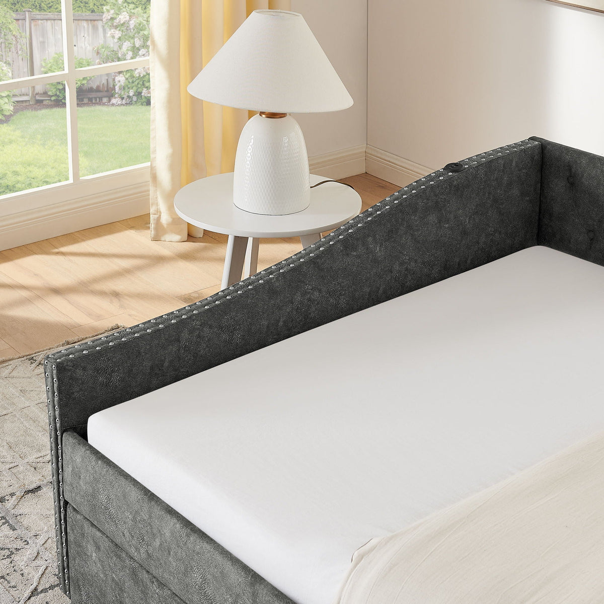 Upholstered daybed in dark gray fabric with nailhead trim and white mattress on Tampa Home & Garden Store