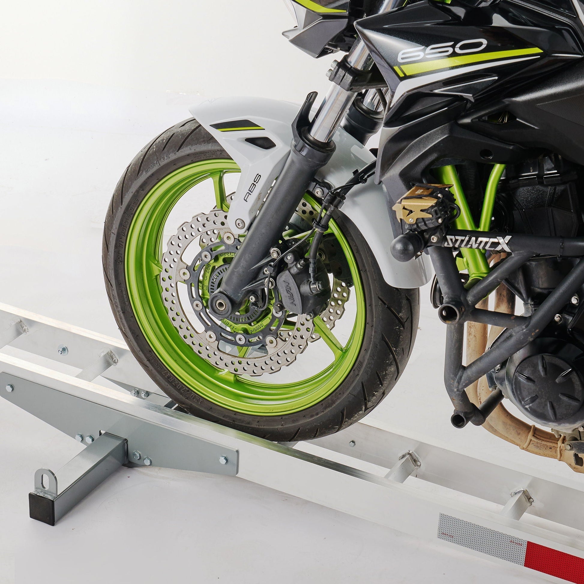 Motorcycle loading ramp with hitch-mount carrier in silver; lime-green wheel and disc brake visible on Tampa Home & Garden Store