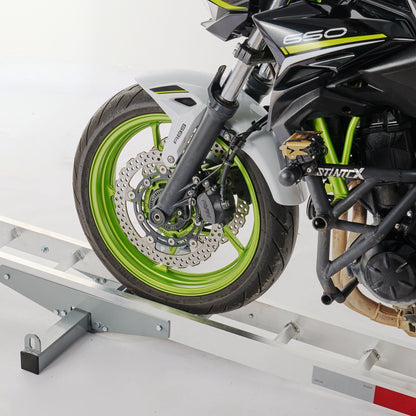 Motorcycle loading ramp with hitch-mount carrier in silver; lime-green wheel and disc brake visible on Tampa Home & Garden Store