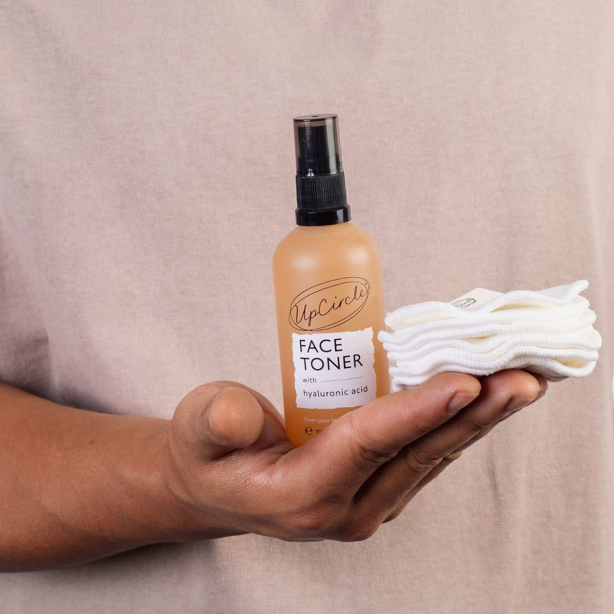 UpCircle Face Toner with hyaluronic acid in amber spray bottle, held with white cloths on Tampa Home & Garden Store