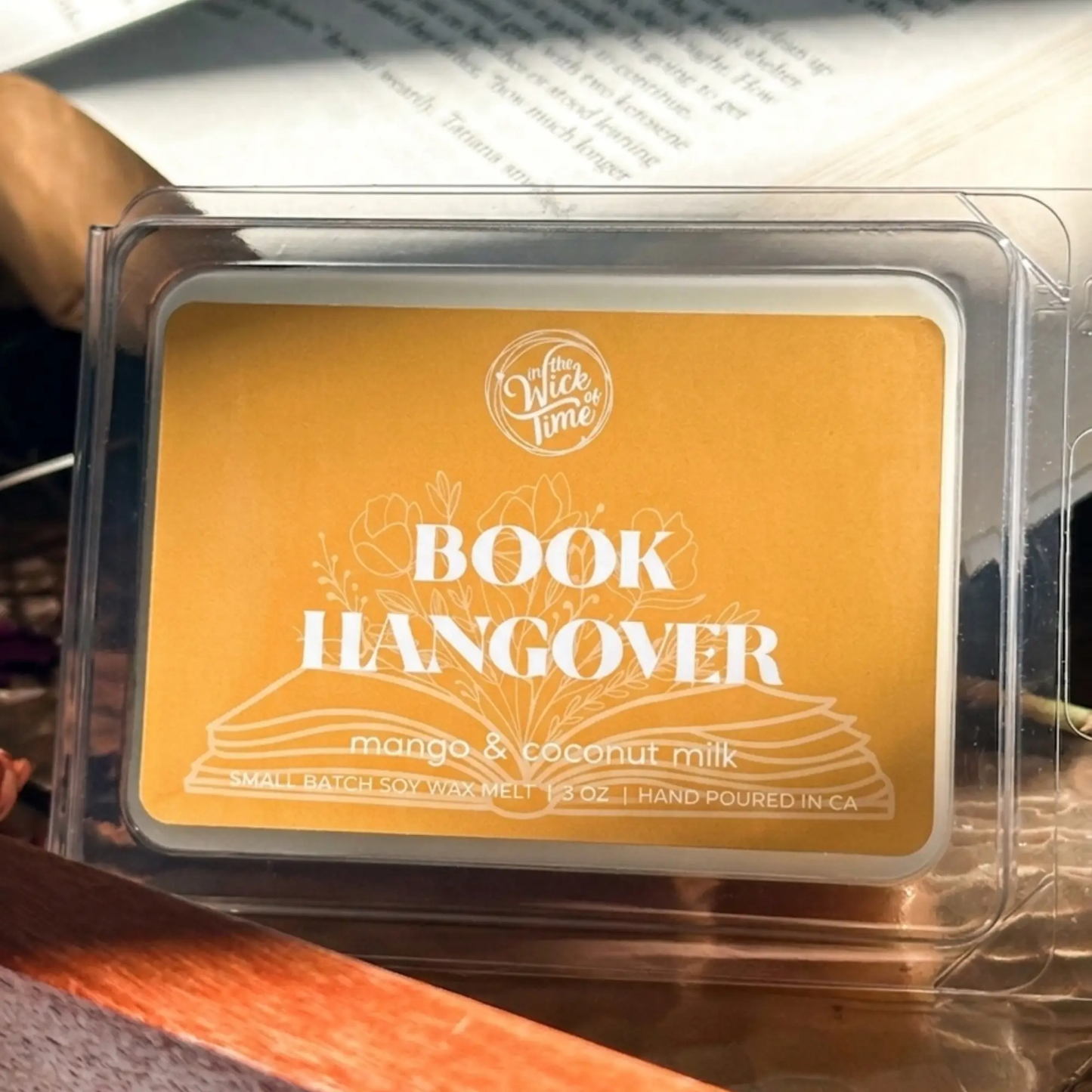 Wax melt Book Hangover Mango Coconut Pineapple by In the Wick of Time with orange label on Tampa Home & Garden Store